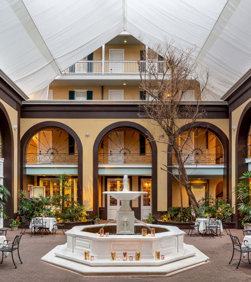 A courtyard with a fountain, seating area, and tree