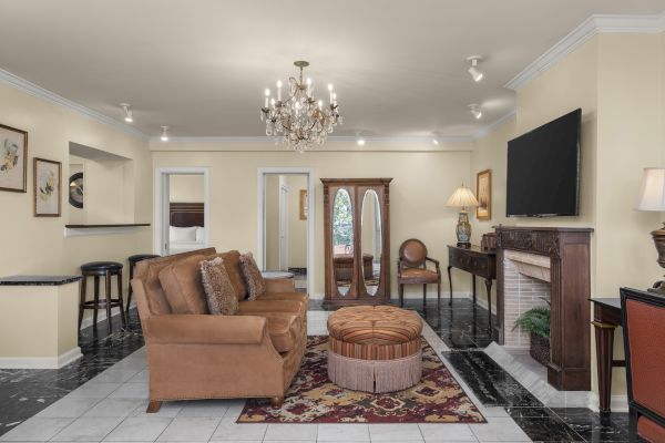 A cozy living room with a brown sofa, chandelier, TV, fireplace, and decor accents, creating a warm and inviting ambiance.