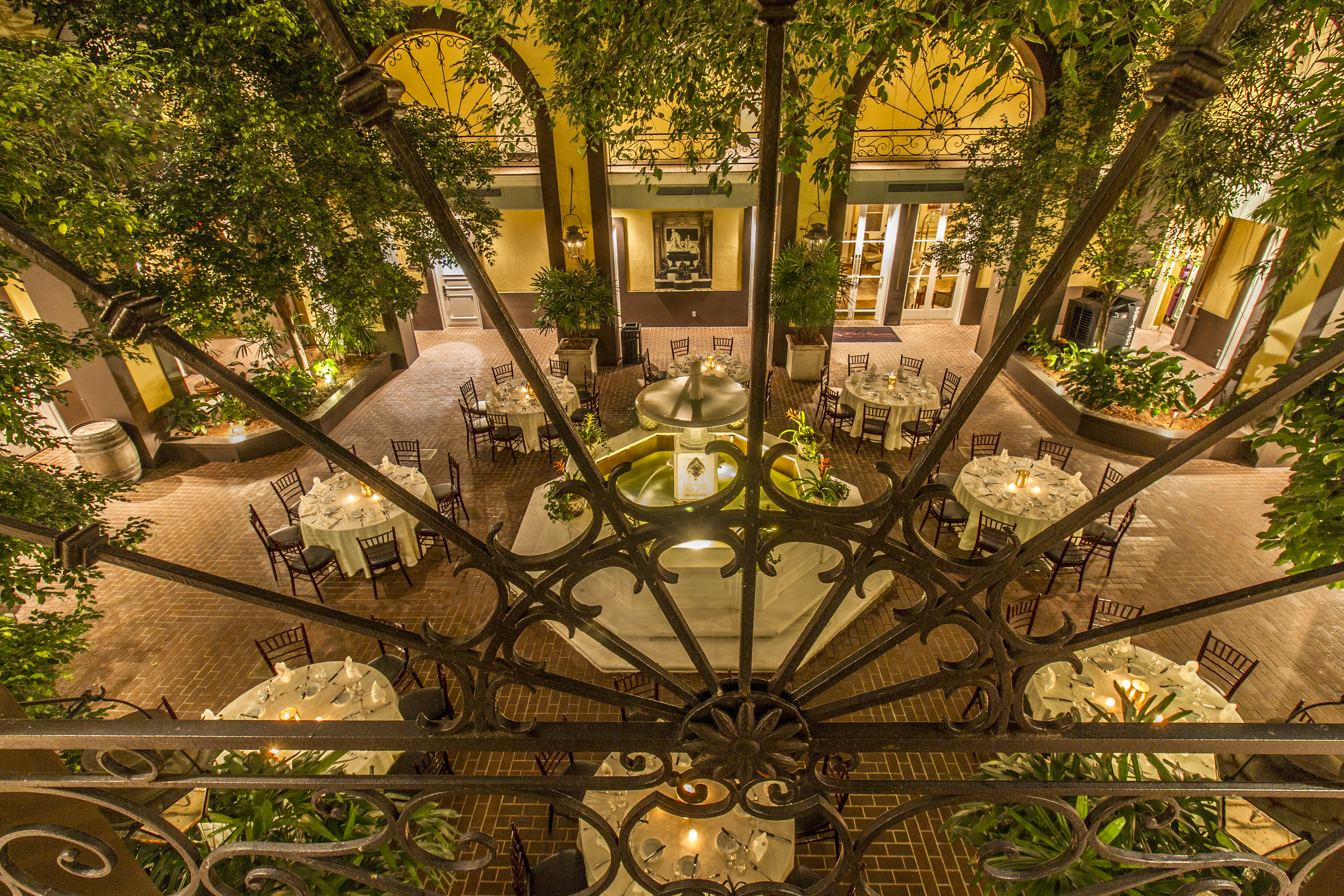 A courtyard with tables and chairs surrounded by trees and a fountain