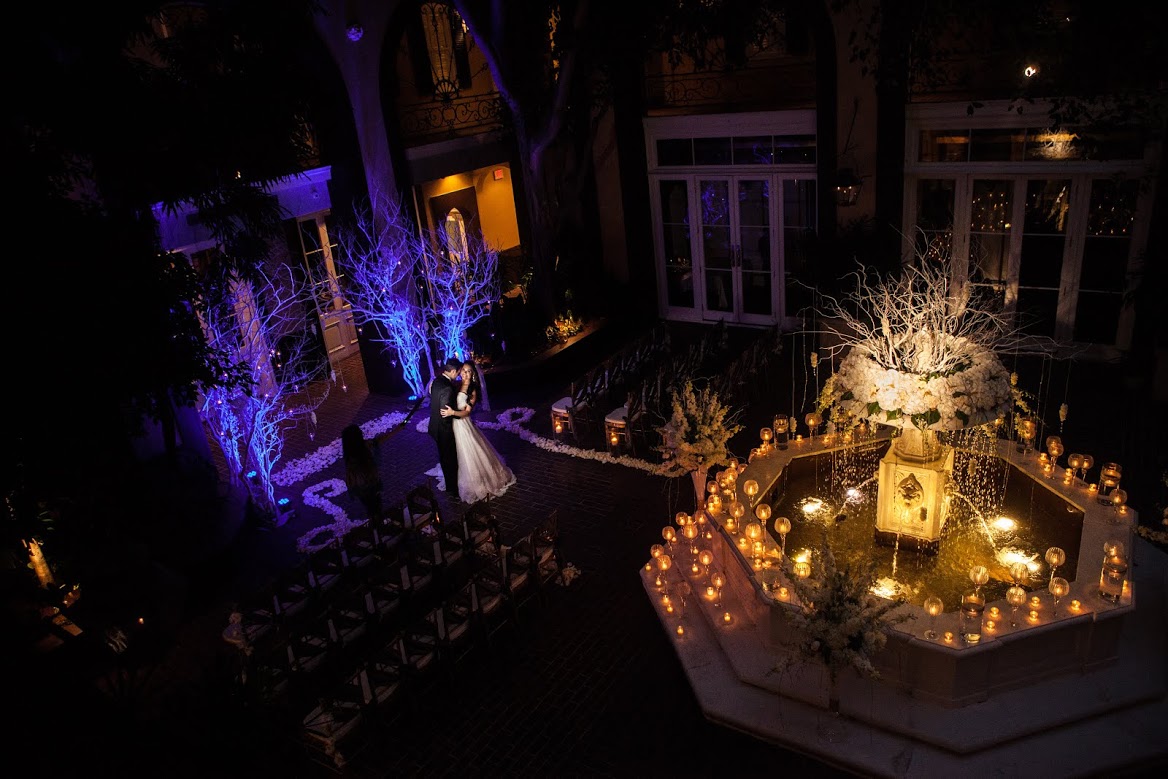 a nighttime view of a courtyard with a fountain and candles