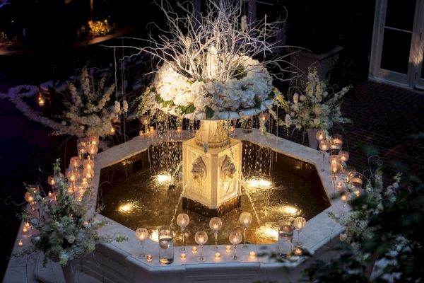 A beautifully decorated fountain with white flowers and lit candles, creating an elegant and romantic ambiance.