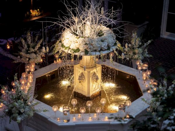 A beautifully decorated fountain with white flowers and lit candles, creating an elegant and romantic ambiance.