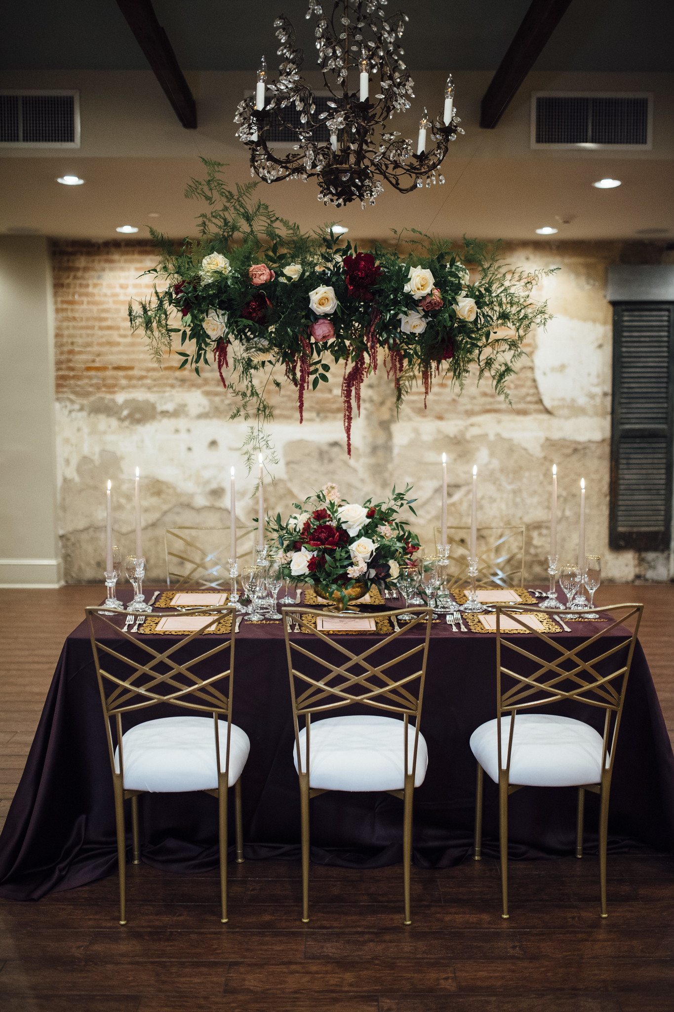 A formal dining table set with flowers, candles, and a chandelier