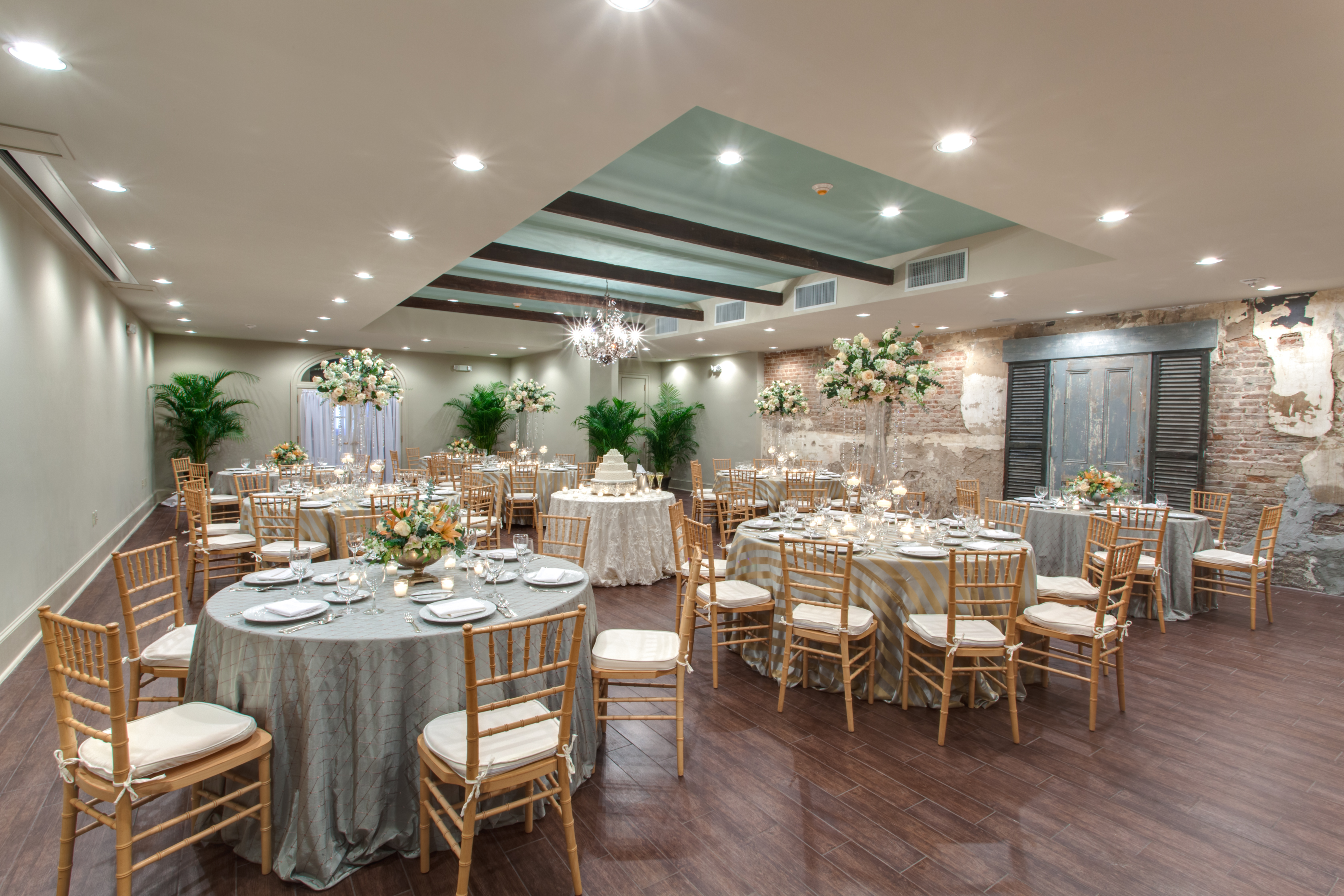 A large room with round tables set for a meal, decorated with flowers and gray tablecloths.