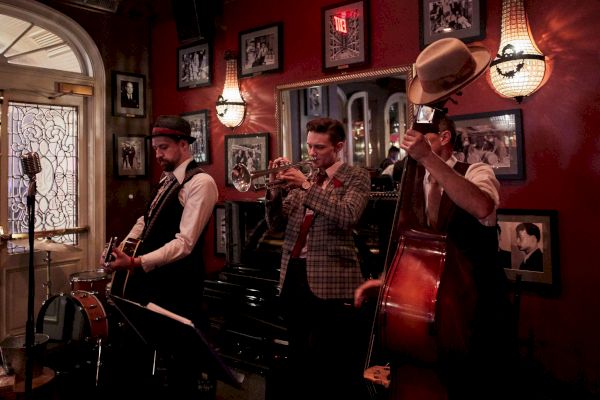A jazz band is playing in a cozy room with vintage decor and framed photos on the walls.