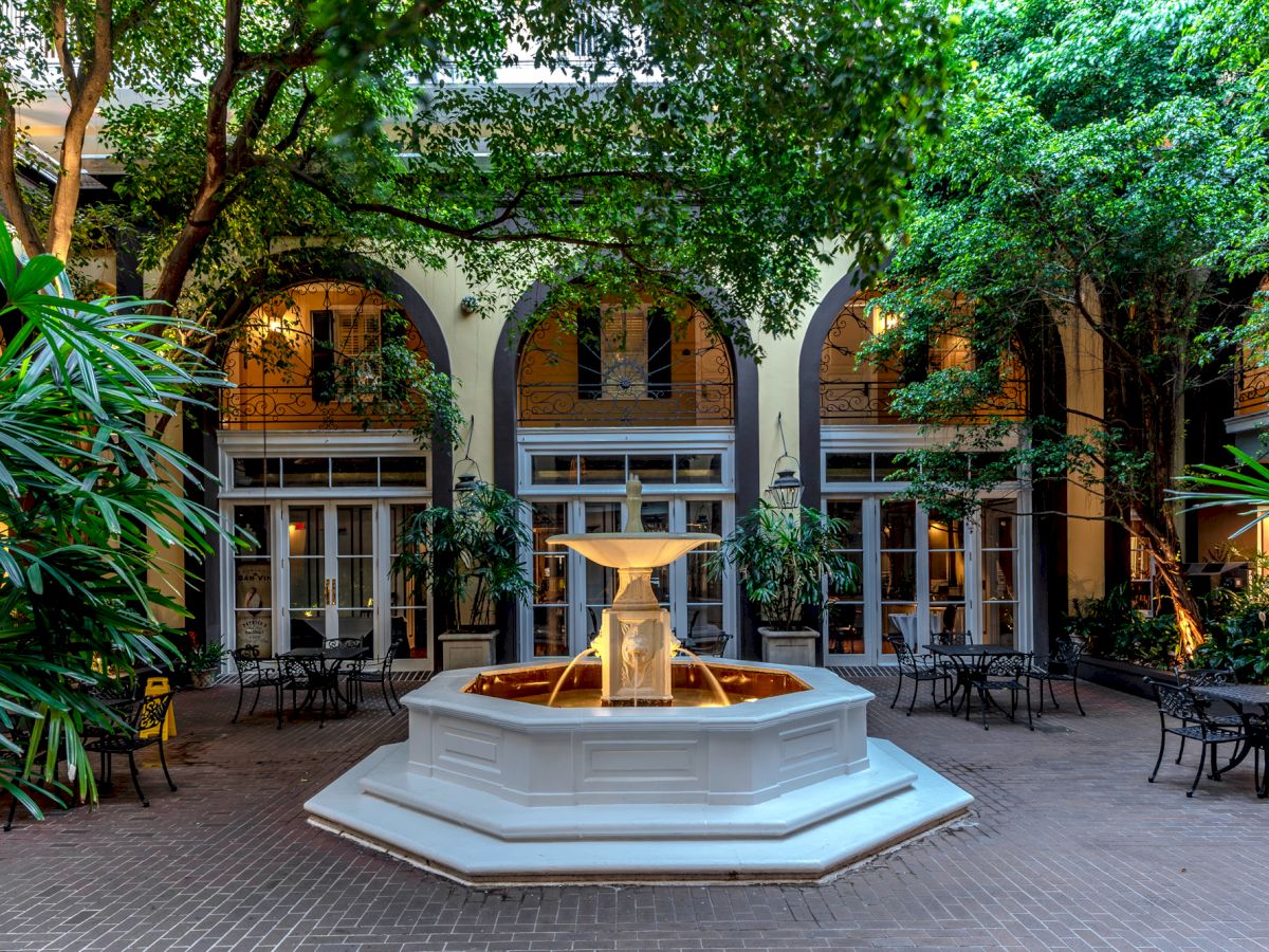 A charming courtyard with a central fountain, surrounded by lush greenery and arched windows, offering a tranquil and inviting atmosphere.