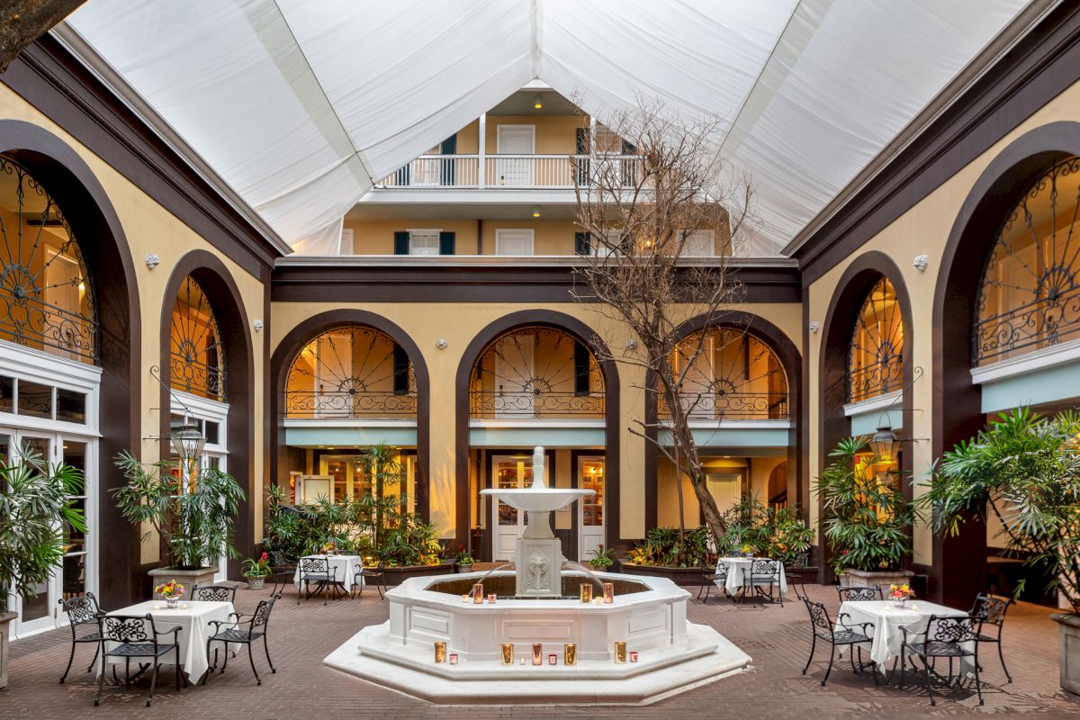 A large indoor courtyard with a fountain, seating areas, and a tree.