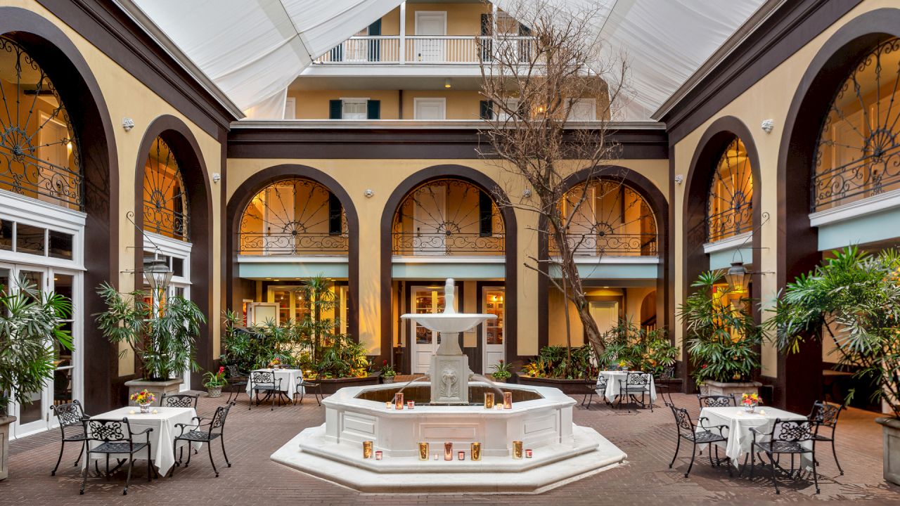 A courtyard with a fountain, outdoor seating, and a tree