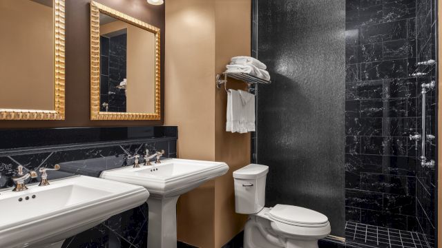A bathroom with two sinks, a toilet, and a shower