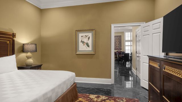 A hotel room with a bed, TV, and lamp.