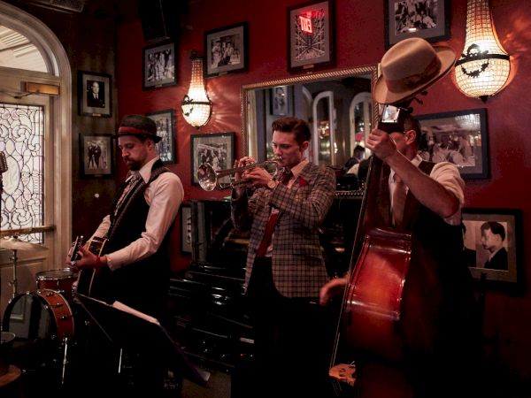 A jazz band is playing in a cozy room with vintage decor and framed photos on the walls.