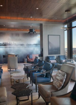 A stylish seating area with multiple chairs and tables, featuring large windows with a scenic view of water and a Ferris wheel outside.