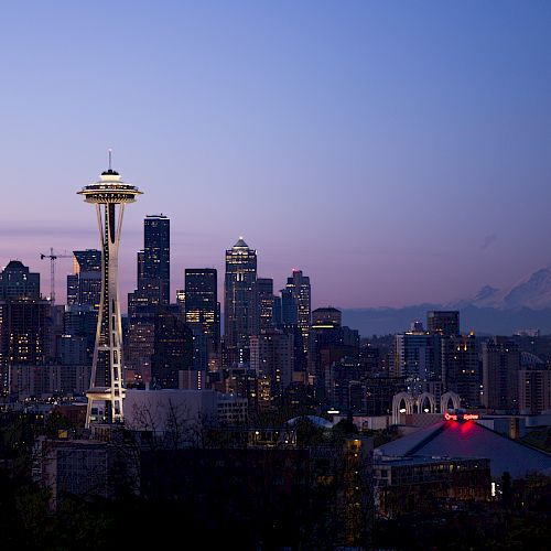 Skyline of Seattle at dusk, featuring the Space Needle and Mount Rainier in the background.